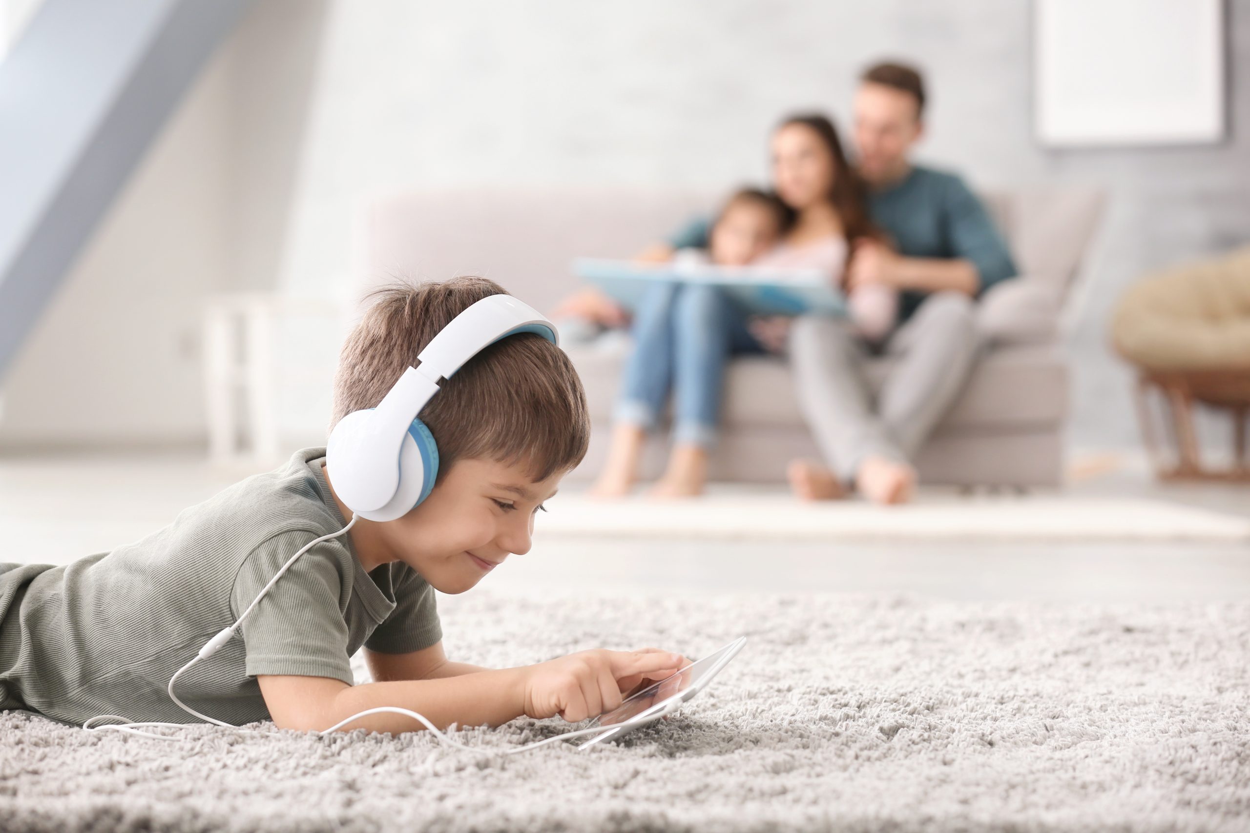 Cute little boy with tablet computer at home on carpet